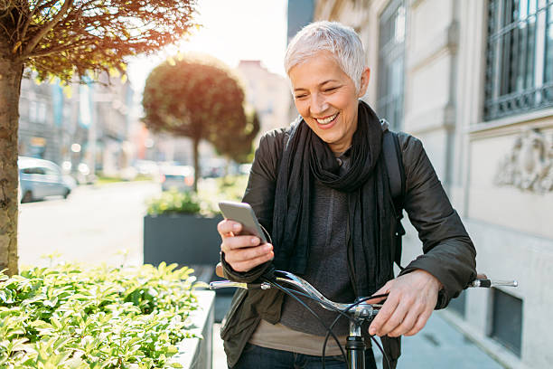 マチュアを使用する女性スマートフォン自転車に乗っています。 - short cycle ストックフォトと画像