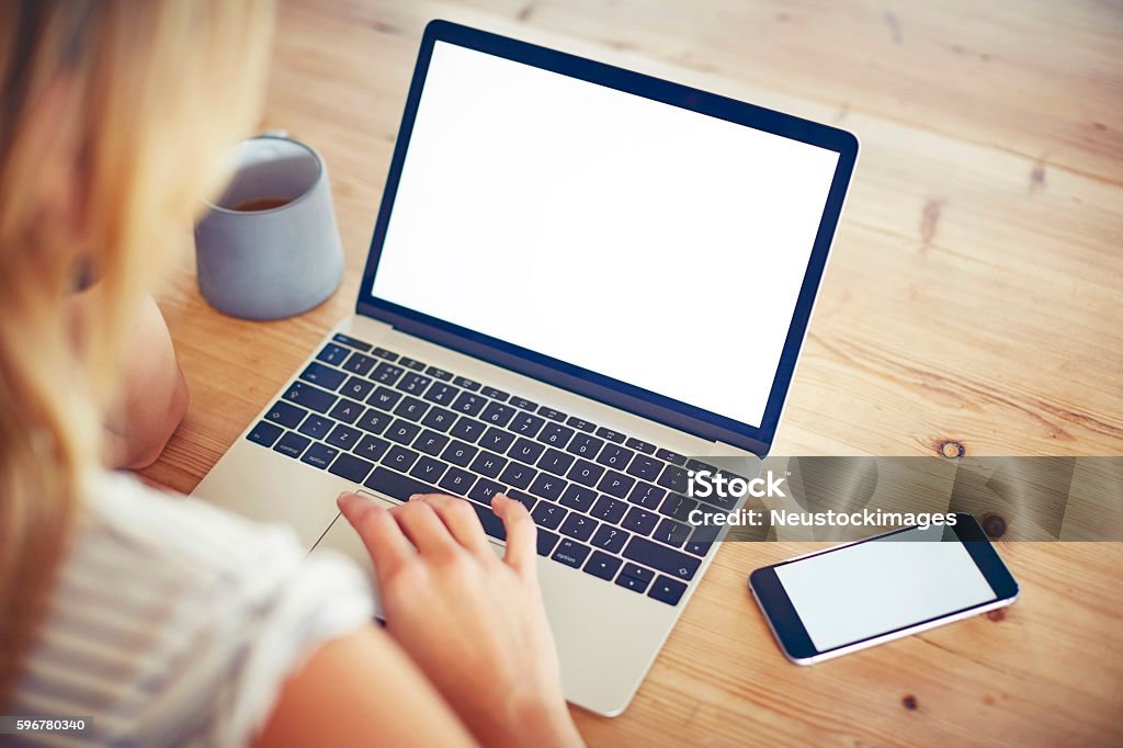 Frau mit Laptop und Smartphone mit leerem Bildschirm am Tisch - Lizenzfrei Laptop Stock-Foto