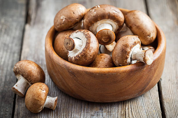 istock Mushrooms in wooden bowl on table. 596780818