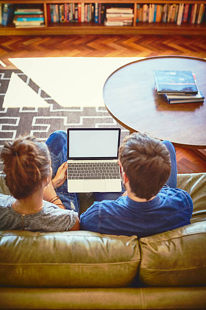 istock Rear view of young couple using laptop on sofa 596781556