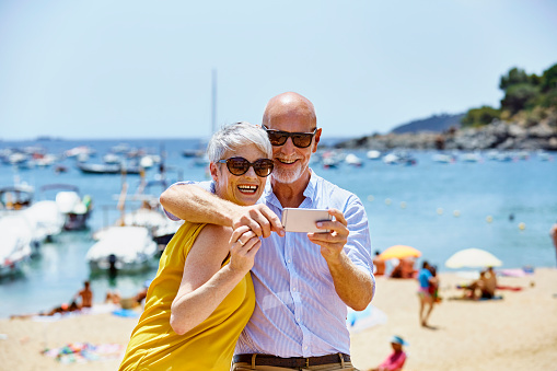 Happy senior couple taking selfie on beach