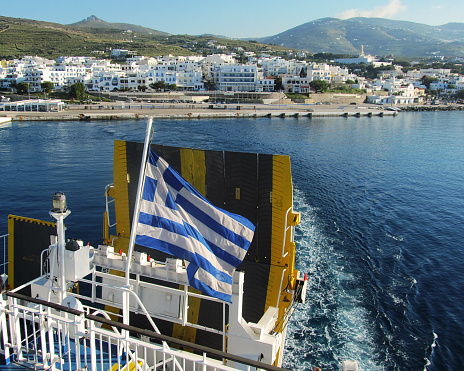 Ferry boat stern on the move with Tinos island on the background