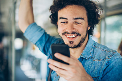 Young man traveling in public transport and checking messsages.