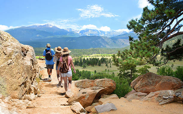 Family on hiking trip in Colorado mountains. People with backpacks hiking  on summer vacation in mountains. Father with his family enjoying time on a trip. Blue sky and high mountains in background. Rocky Mountain National Park, Colorado, USA. rocky mountain national park stock pictures, royalty-free photos & images