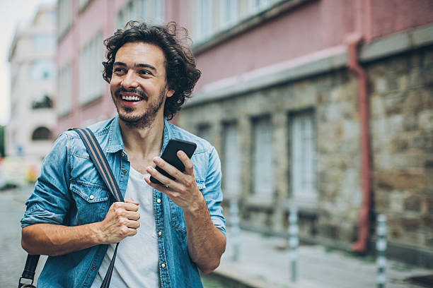 istock Cheerful man texting on the street 596788012