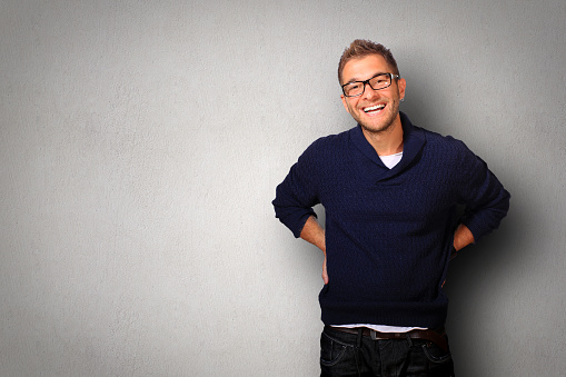 Young man in a blue sweater and jeans smiles