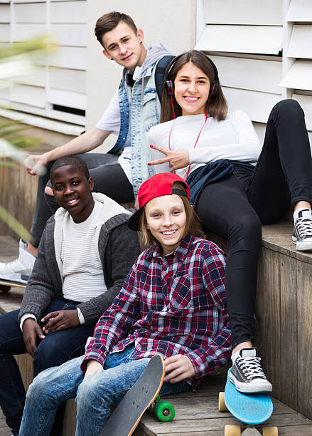 istock girl and three boys hanging out outdoors and discussing somethin 596789408