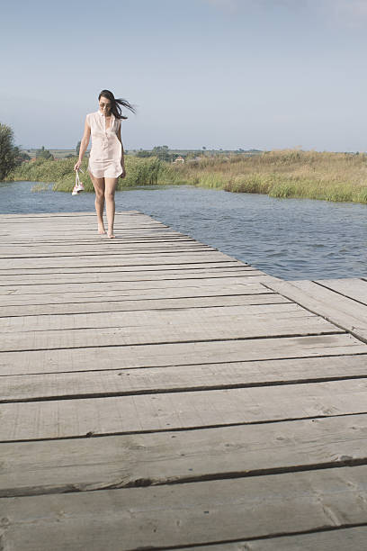 istock Girl walking barefoot on the dock 596790598