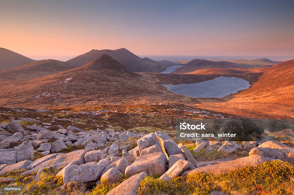 Sunrise over the Mourne Mountains and lakes in Northern Ireland Sunrise over the Mourne Mountains and lakes in Northern Ireland. Photographed from the peak of Slieve Loughshannagh. Mourne Mountains Stock Photo