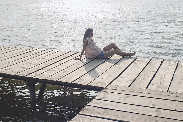 istock Young woman sitting alone by the sea 596791112
