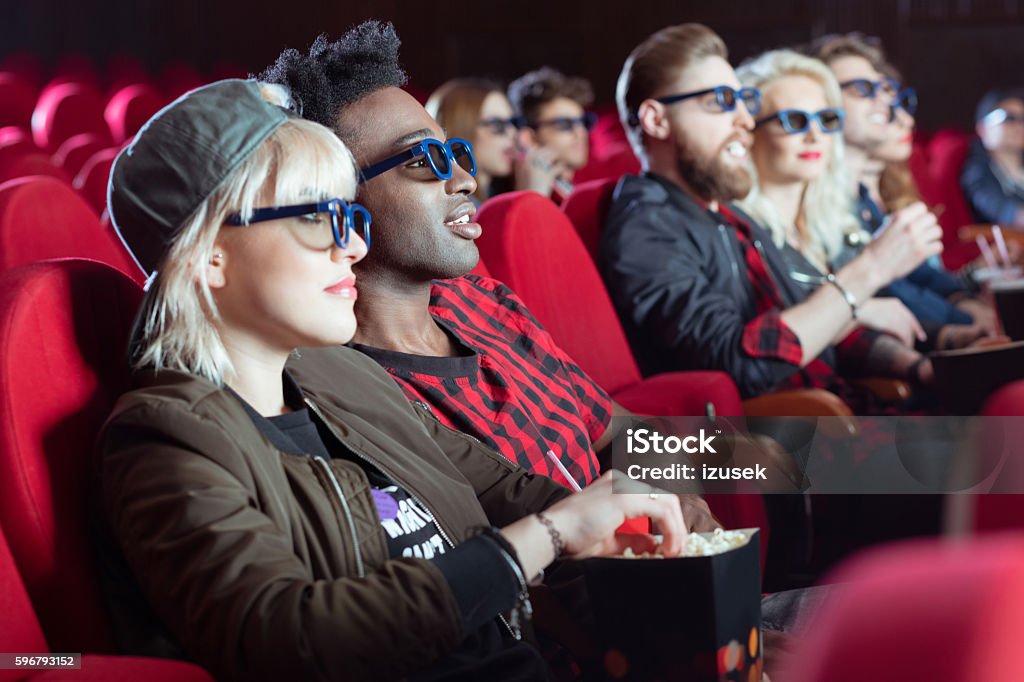 Multi ethnic group of people in the 3d movie theater Multi ethnic group of young people in the 3D movie theater. Focus on blonde young woman and her afro american boyfriend. Movie Stock Photo