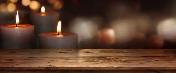 Wooden table with burning candles against a dark background