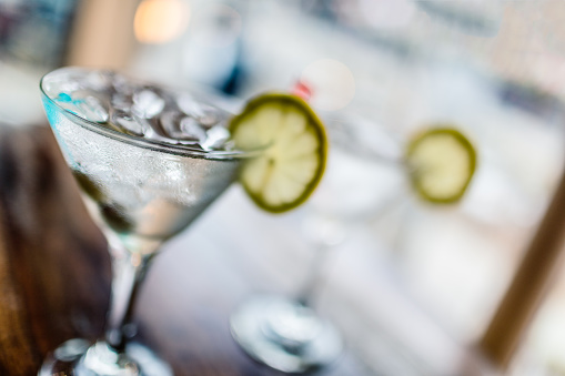 Two glasses of classic martinis with ice on a hot Summer day. Selective focus on the foreground glass.