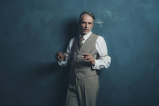 homem de negócios retrô estilo anos 1920 fumando charuto e segurando uísque de vidro. - 20s businessman suit people - fotografias e filmes do acervo