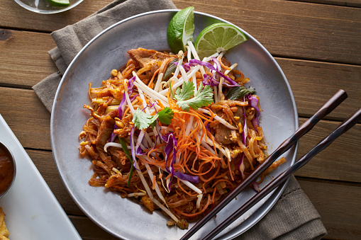 beef pad thai shot from overhead view on wooden table in flat lay composition.