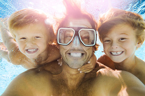 papà e figli che si divertono a fare un selfie sott'acqua - swimming pool swimming summer underwater foto e immagini stock