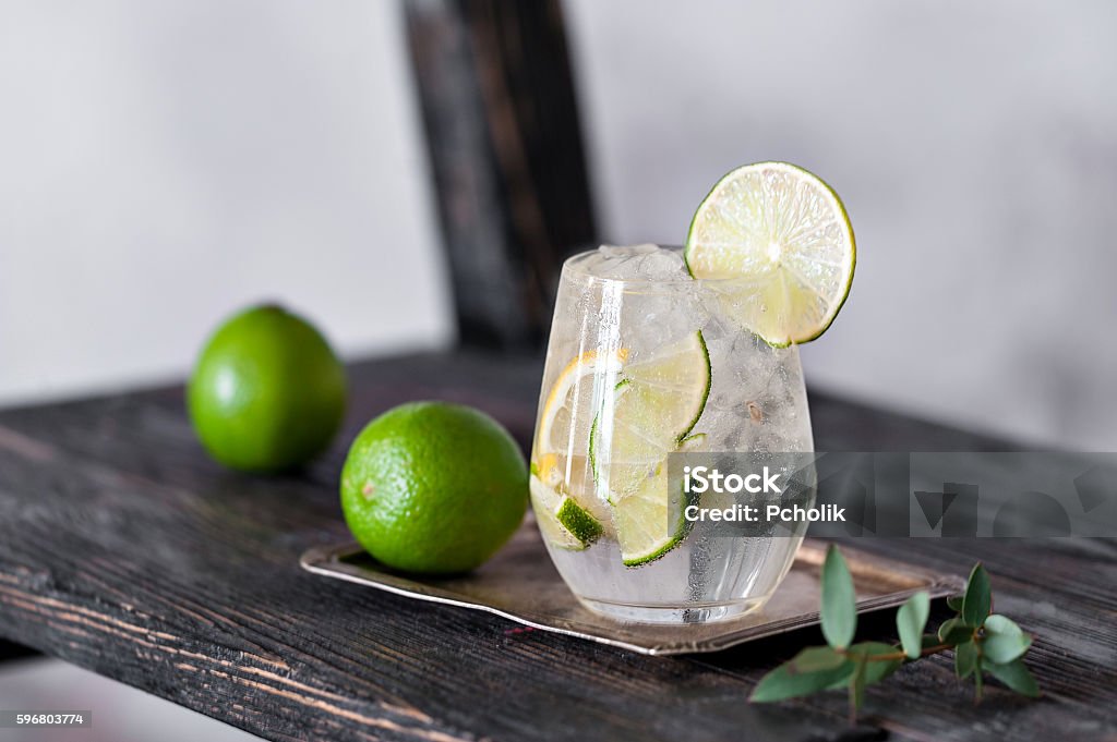Cold cocktail with lime, lemon, tonic, vodka and ice Cold cocktail with lime, lemon, tonic, vodka and ice on vintage background Gin Stock Photo