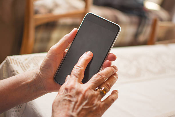 istock Close up of a wrinkled finger touching a smartphone. 596807122