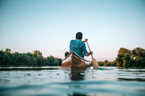 Man paddling a canoe on a lake.