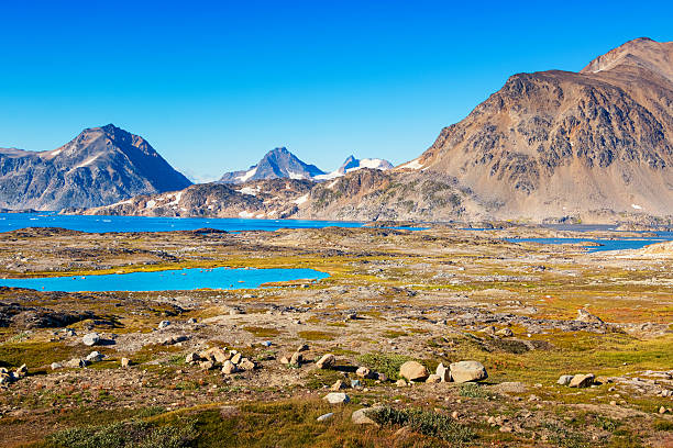 Landscape photo with mountains and barren land during summer at Kulusuk Island, eastern Greenland, on a clear blue sky day.