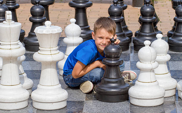 enfant jouer à un jeu d’échecs avec des échecs géants à l’extérieur - chess leisure games chess queen skill photos et images de collection
