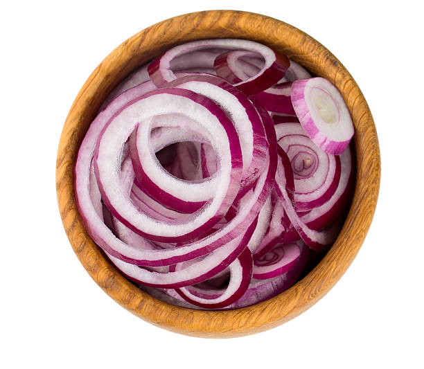 red onion slices in a wooden bowl isolated on white stock photo