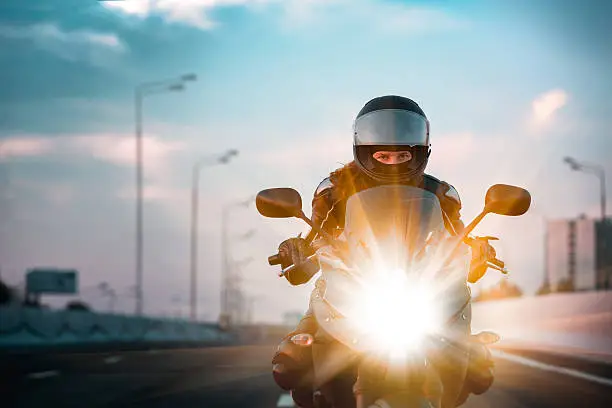 Photo of Woman drives on a motorcycle on a morning highway