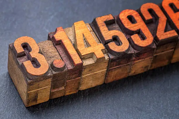 numerical representation of the pi number - vintage letterpress wood type against a slate stone