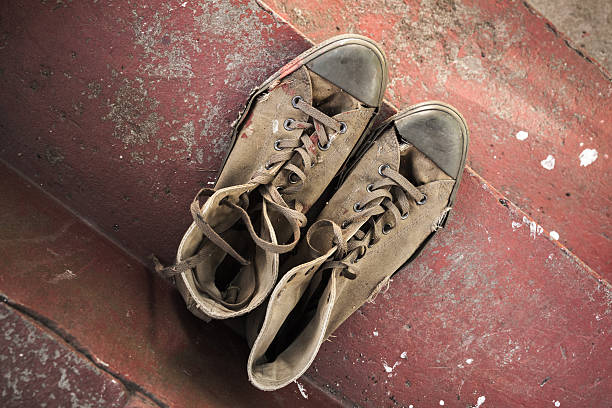 istock Pair of old sneakers standing on red concrete 597223116