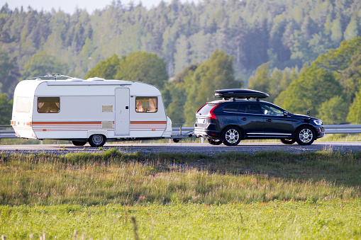 Katrineholm, Sweden- June 7, 2015: Travel trailer pulled by a car that also has a ski box on the roof for extra space