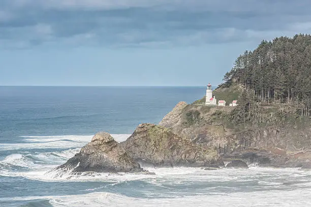 Coastal view of Heceta head lightstation in Yachats, Oregon with crashing waves and fog during storm clouds
