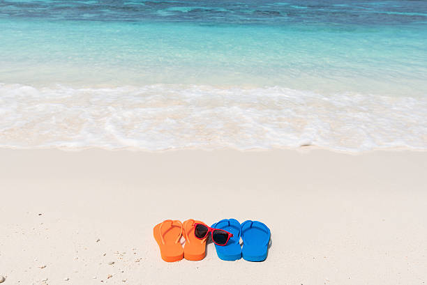 istock Sunglasses and colored sandals on tropical beach 597237904