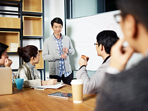 young asian businessman facilitating a discussion young asian businessman facilitating a group discussion or training in office. mediation photos stock pictures, royalty-free photos & images