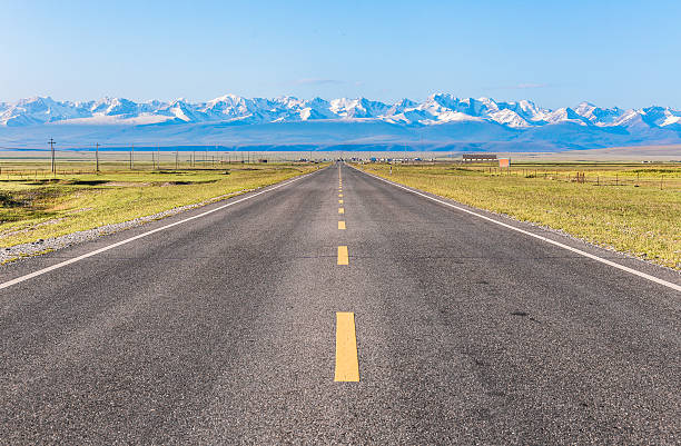 istock Straight road under the snow mountain. 597240694