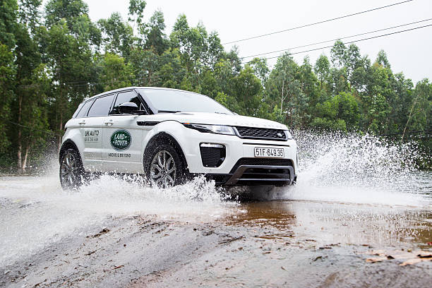 E.m. 2016 because Hanoi, Vietnam - July 13, 2016: Range Rover (Land Rover) Evoque 2016 car crossing water dam on the test road in mountain area in Vietnam. evoque stock pictures, royalty-free photos & images