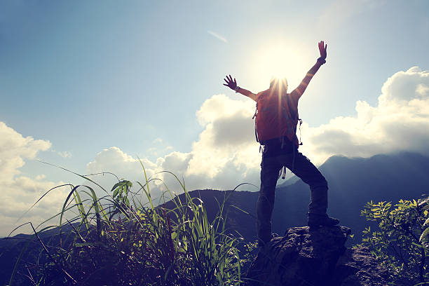 istock successful young woman backpacker open arms on mountain peak 597242046