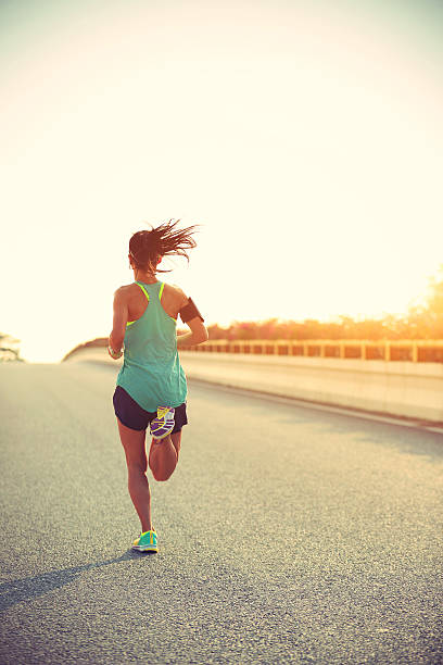jóvenes gimnasio mujer corredor corriendo en salida del sol carretera - ponytail hairstyle female back fotografías e imágenes de stock