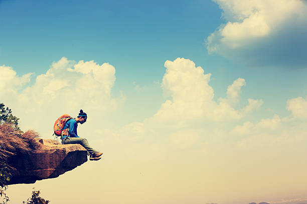 istock woman hiker looking from the mountain peak cliff 597244242