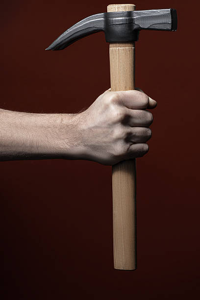 istock Man's hand holding hammer on red background 597245026