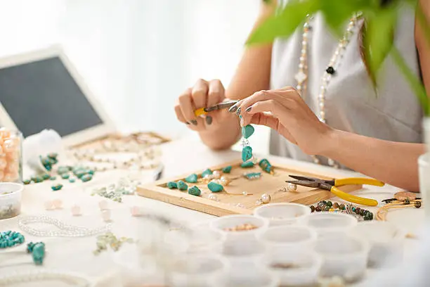 Hands of woman using pliers when assembling earring