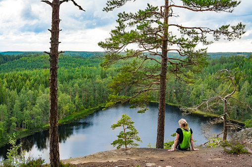 Woman looking at lake view on high cliff in National Park in Finland