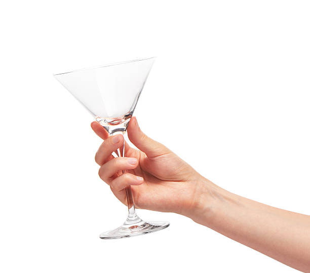 istock Female hand holding empty clean martini glass against white 597252204