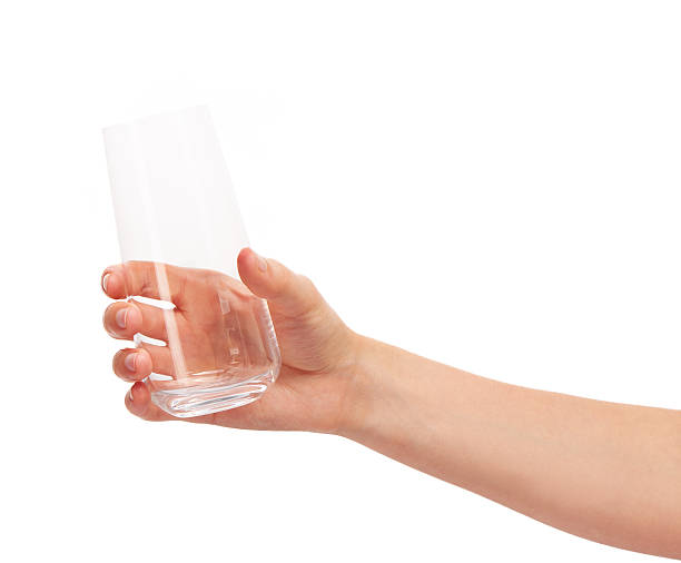istock Female hand holding empty clean drinking glass against white 597252234