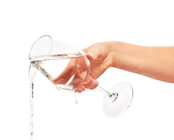 Water pouring from full wine glass in woman's hand