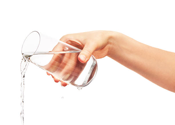 istock Water pouring from full drinking glass in woman's hand 597252538