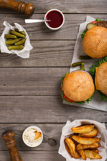 istock different hamburger on wooden table with sauces, fries and pickl 597255238