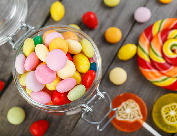 istock Different colorful candy in glass jar on wooden table 597255708
