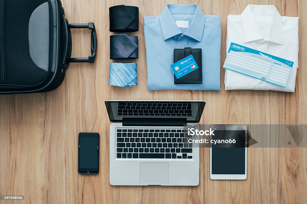 Business travel Planning a business trip: bag, formal clothing, credit cards and plane tickets on a desk with laptop, smartphone and tablet, traveling and technology concept Business Travel Stock Photo