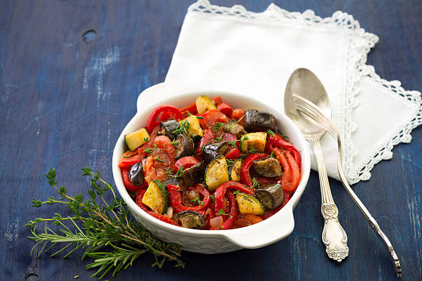 Ratatouille on a dark blue background Ratatouille, a traditional French dish of fresh vegetables in a white ceramic bowl on a dark blue background ratatouille stock pictures, royalty-free photos & images