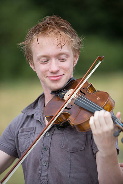 istock Vertical portrait of young redhead boy playing violin 597259890